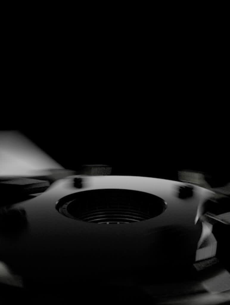 Close-up of a glossy black mechanical component with a central circular hole, set against a dark background. The lighting highlights its smooth surface and intricate detailing, giving it a futuristic appearance.
