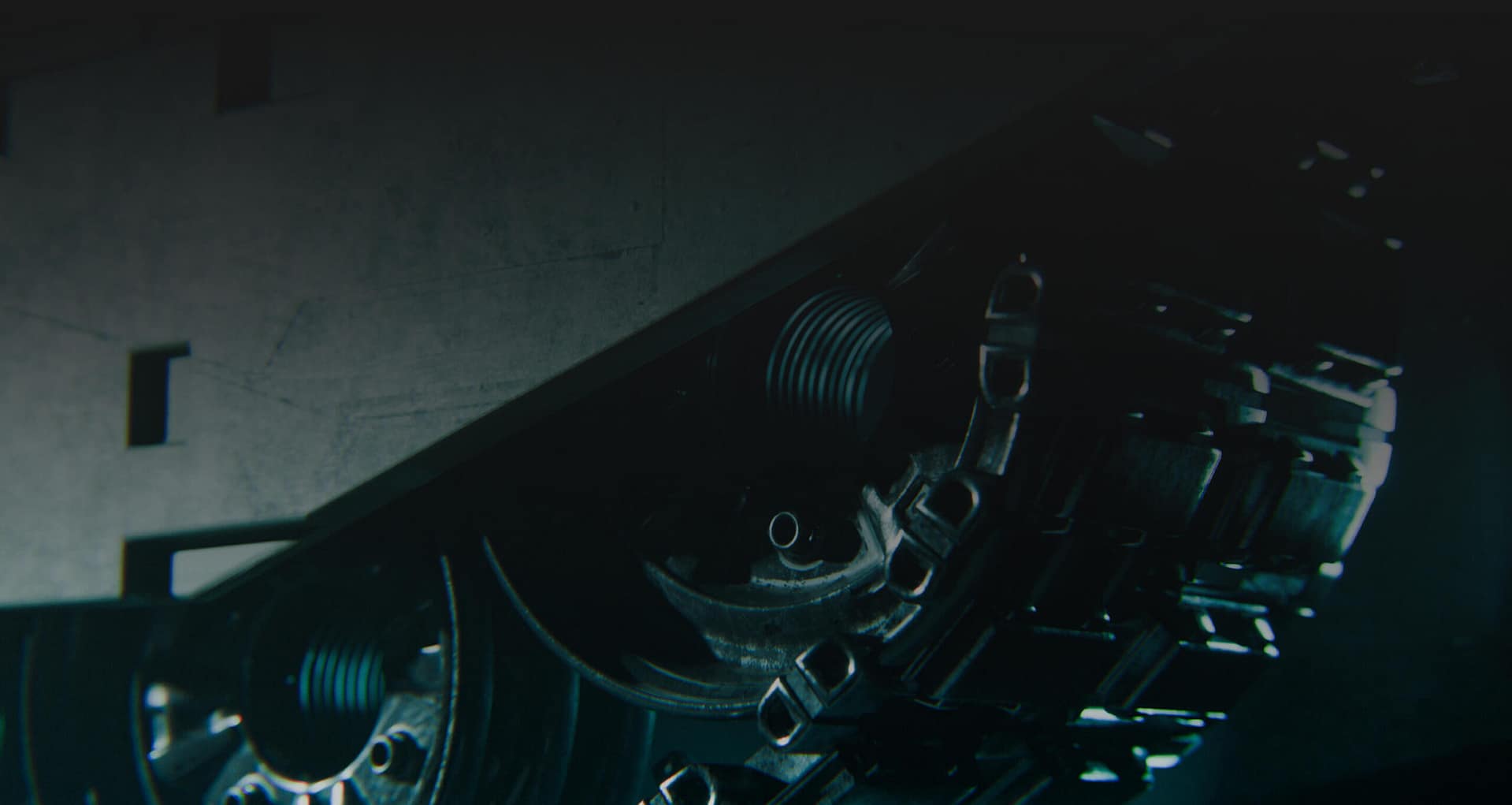 Close-up view of the wheels and metal tracks of a tank or armored vehicle, partially in shadow, emphasizing the intricate mechanical details and rugged texture.