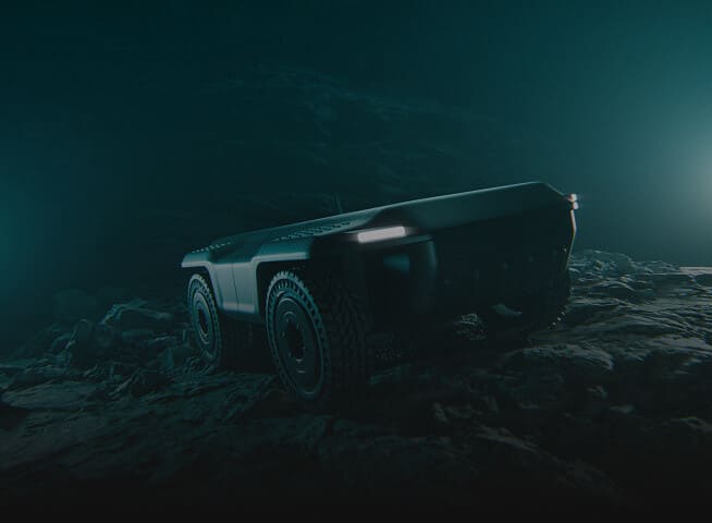 A rugged, autonomous, four-wheeled robotic vehicle navigates a rocky, dimly lit terrain with a blue-green tint and focused headlights illuminating the ground.