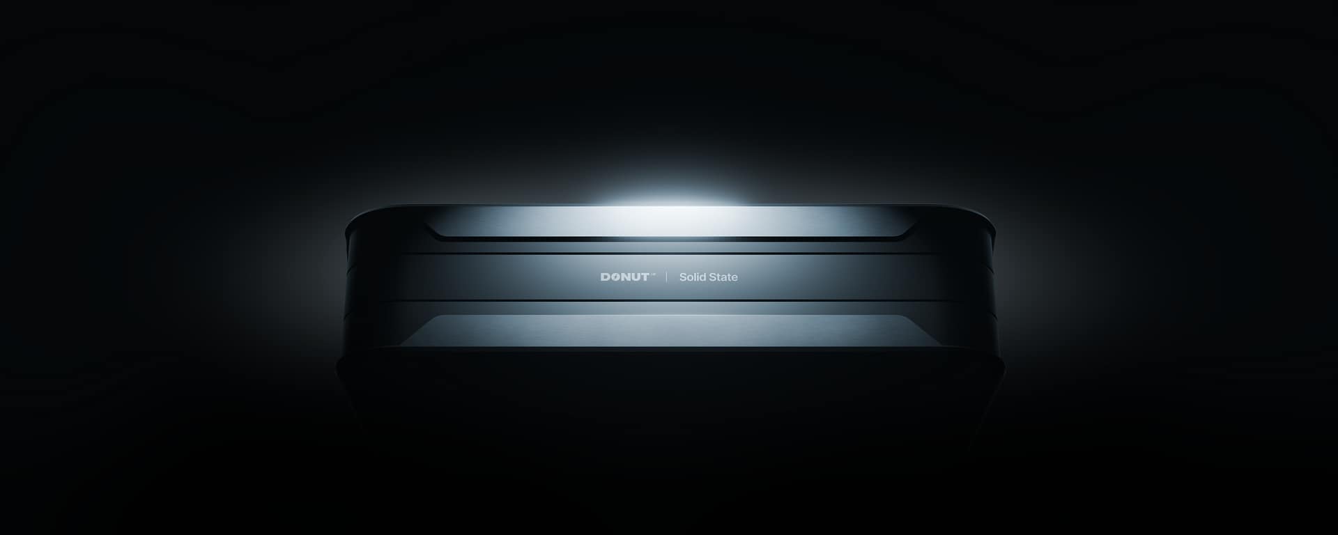battery_hero_dark A sleek, rectangular electronic device labeled "DONUT Solid State" is illuminated dramatically against a dark background, highlighting its modern, metallic design.