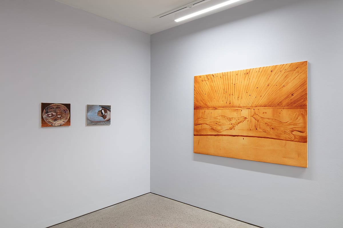 Installation view of ‘Iiris Riihimäki: Tea Bladder’ with oil paintings on a grey wall.