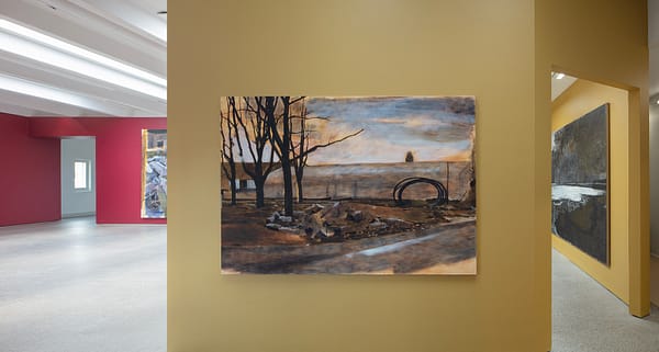 Installation view from the exhibition "Thomas Nyqvist: Painovoima" with a landscape painting of a building site called "Group" hanging on a yellow wall.