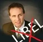 A man in a suit smiles at the camera. The word "LIBEL" is written across the image in large white letters, with a red "X" crossing it out. The background is dark and blurred.
