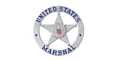 A silver badge with a five-pointed star in the center, displaying the words "United States Marshal" in blue letters around the star, and a small U.S. flag emblem in the middle.