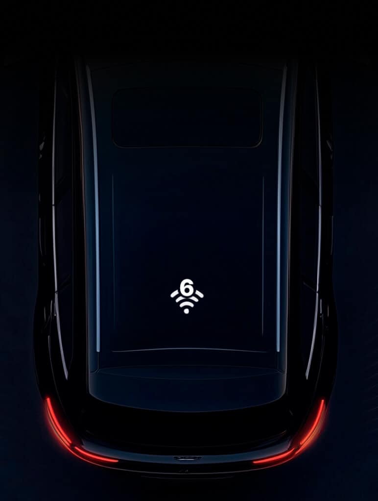 A darkly lit image of a car roof, showcasing a Wi-Fi 6 symbol in the center, suggesting connectivity. The car's rear lights create a red glow at the bottom, adding contrast to the sleek, reflective surface.