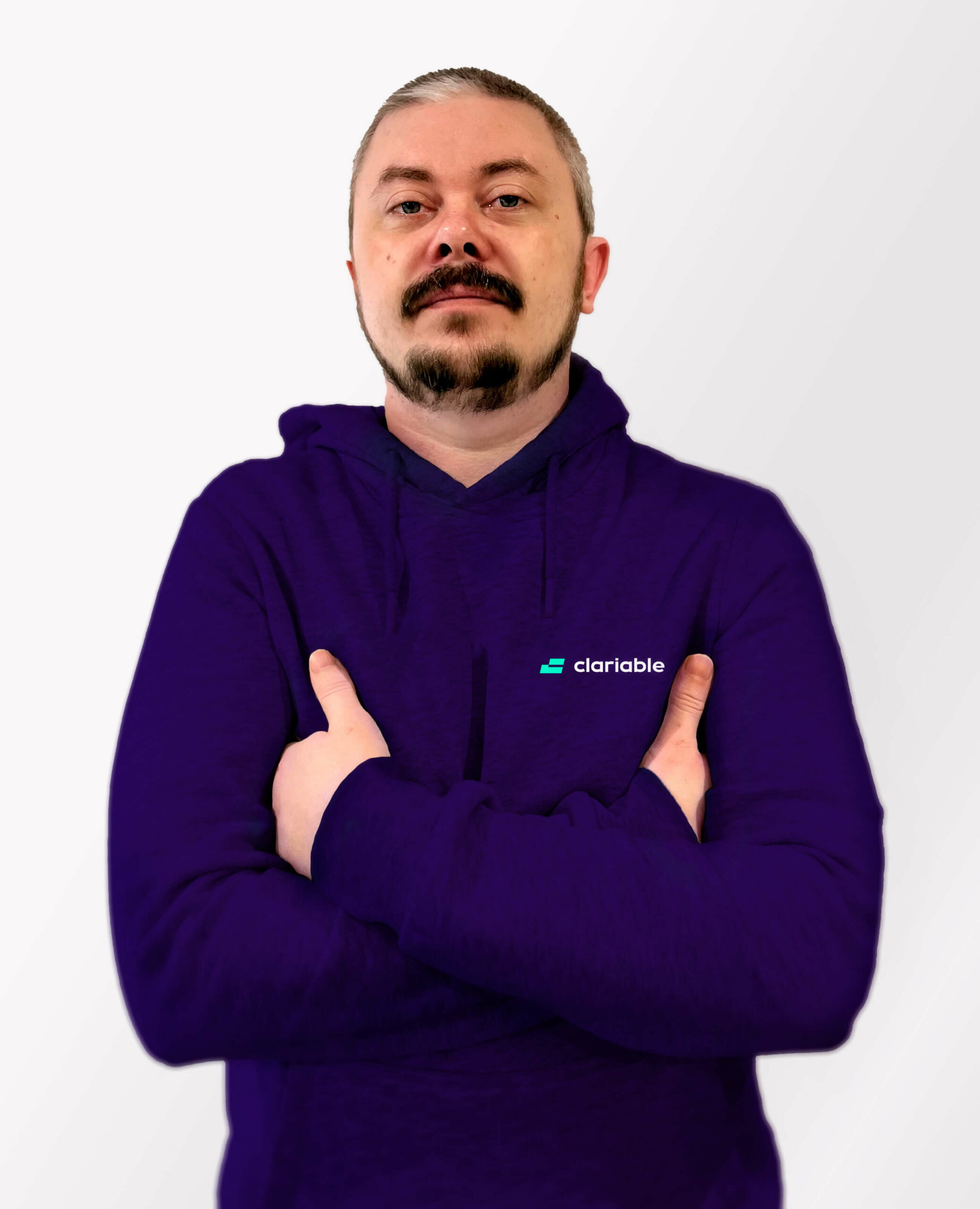 Dmitry A person with short hair and a goatee stands confidently with arms crossed, wearing a purple hoodie with a small logo on the chest. The background is a light gray gradient.