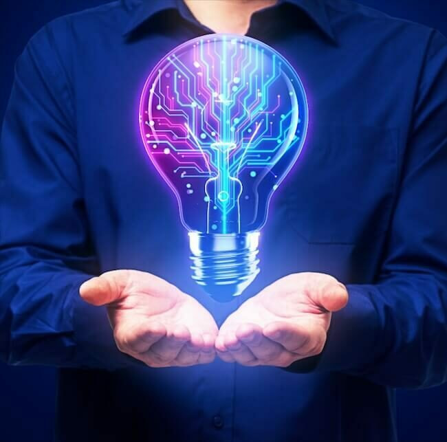Phase 1 Initial Discovery and Strategy A person in a blue shirt holds their hands open, and a glowing light bulb with circuit patterns floats above them against a dark background. The bulb symbolizes innovation and technology.