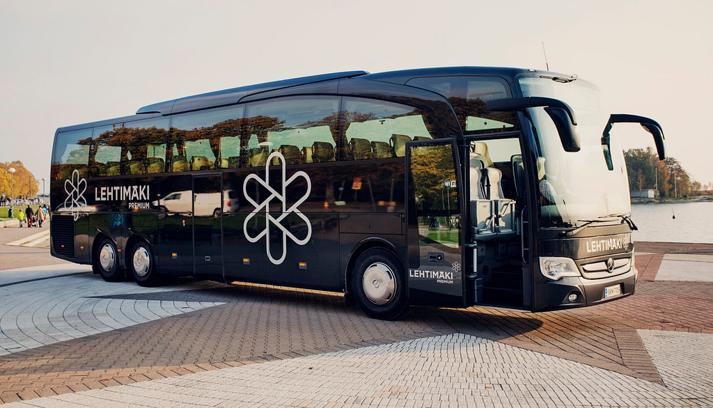 Musta kiertoajelubussi pysäköitynä parkkipaikalle.