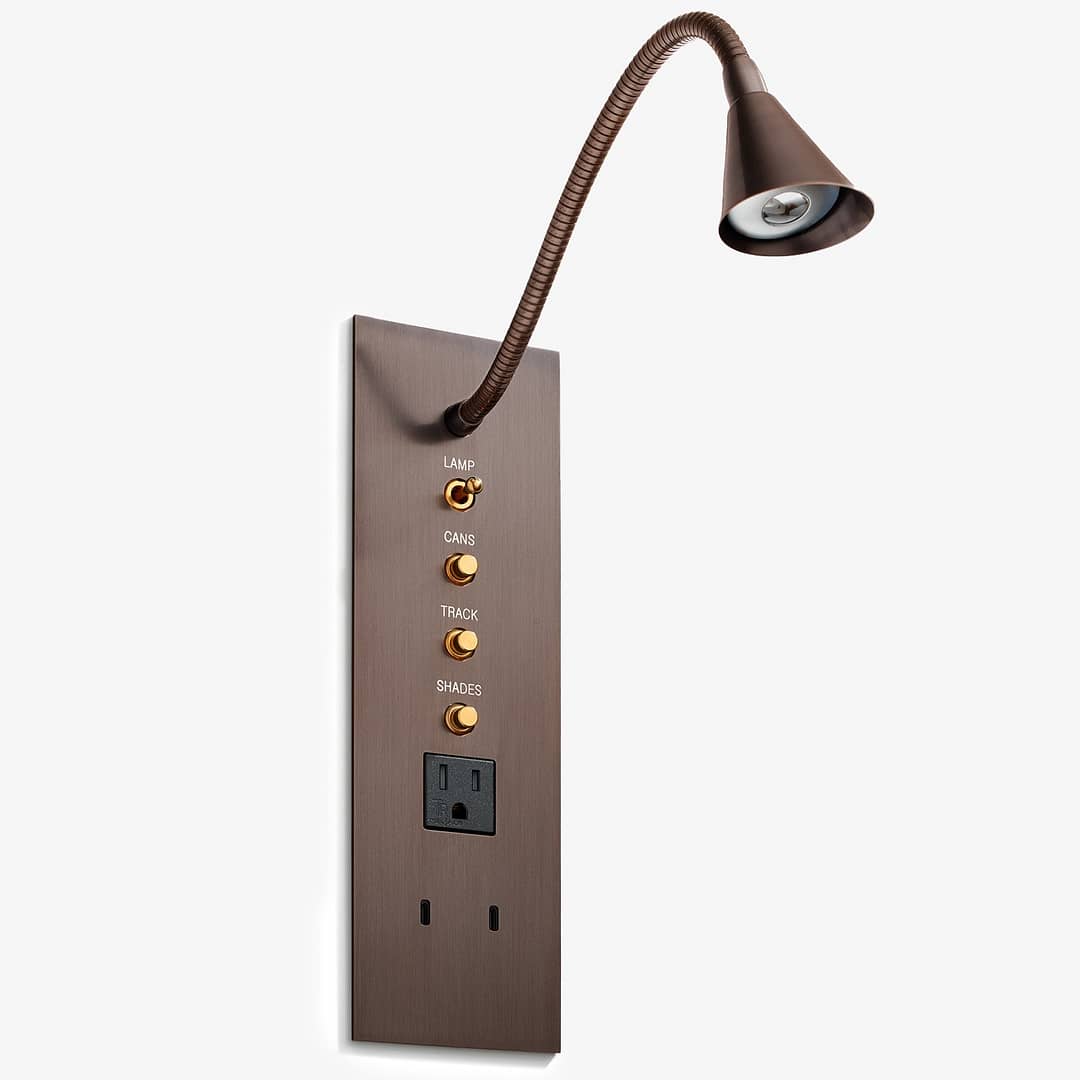 A contemporary wall-mounted control panel with integrated flexible-neck reading lamp, buttons labeled 'lamp,' 'cans,' 'track,' and 'shades,' and an electrical outlet.