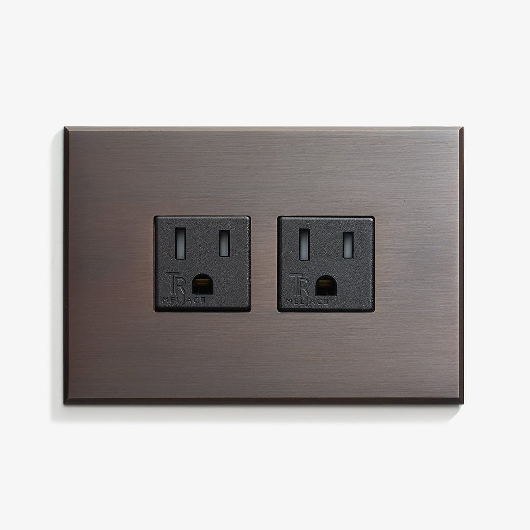 A sleek wall plate with a metallic finish featuring two standard electrical outlets. Both outlets are black with three slots for electrical plugs. The overall design is modern and minimalist.
