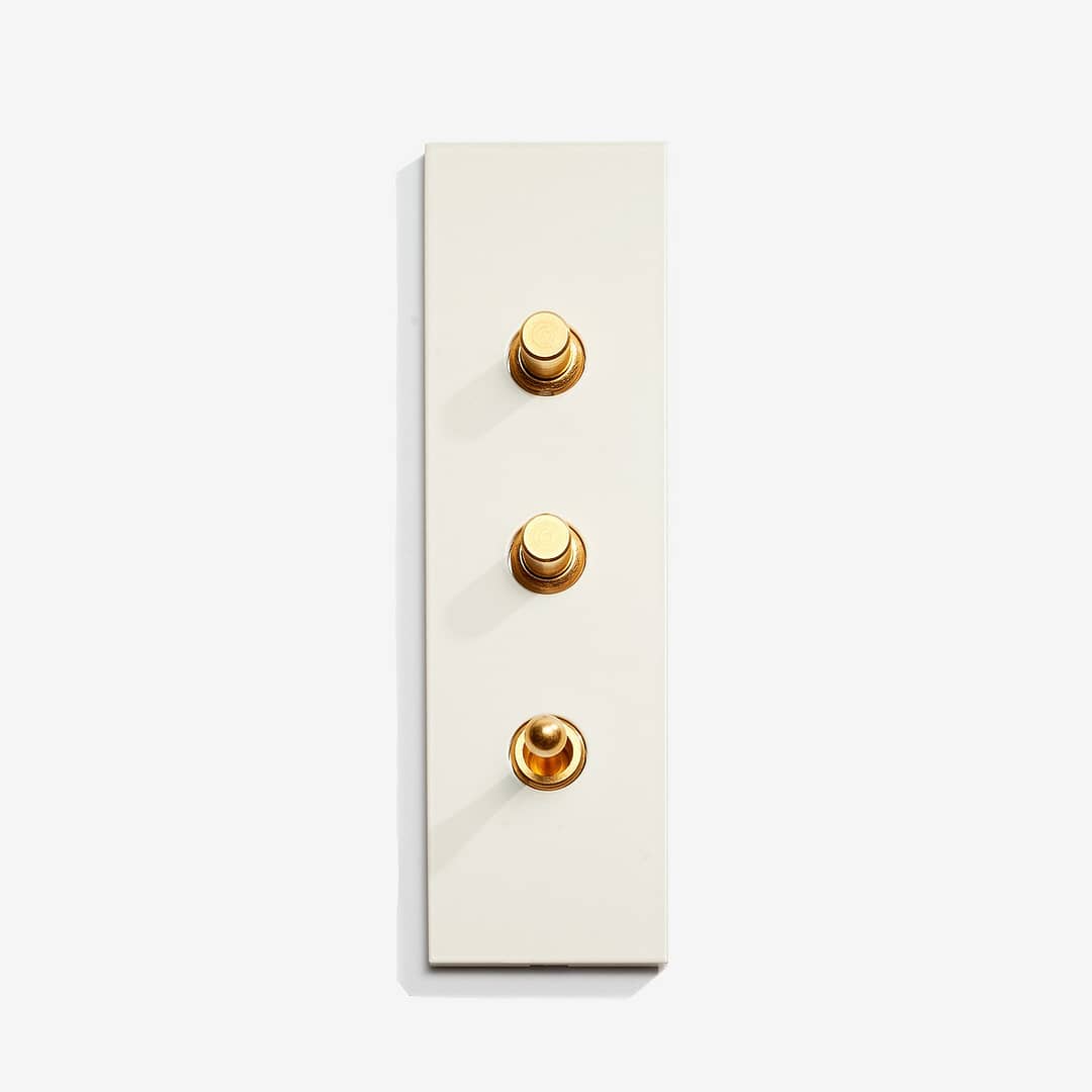 A white wall plate with three gold buttons.