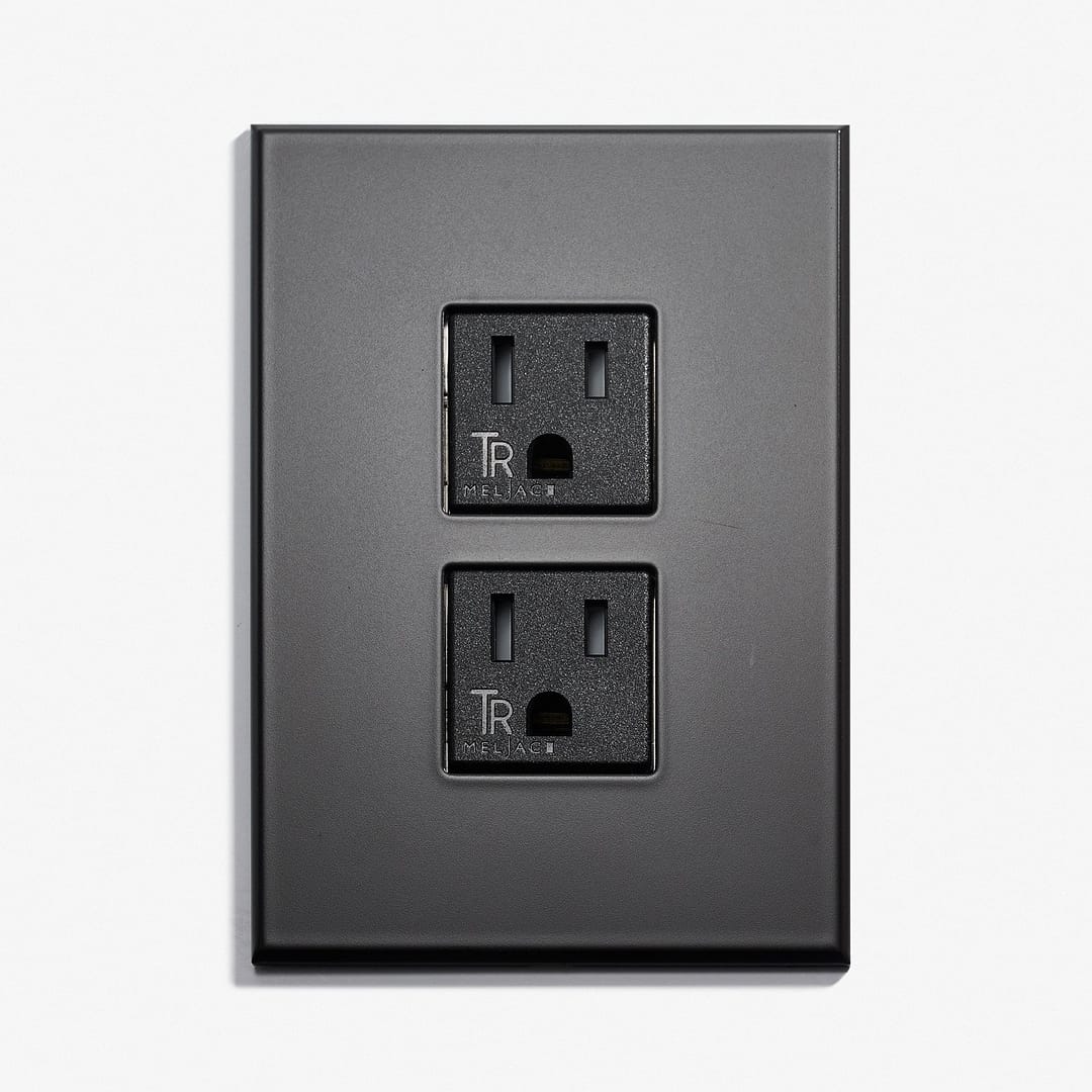 A black wall plate with two outlets on it.
