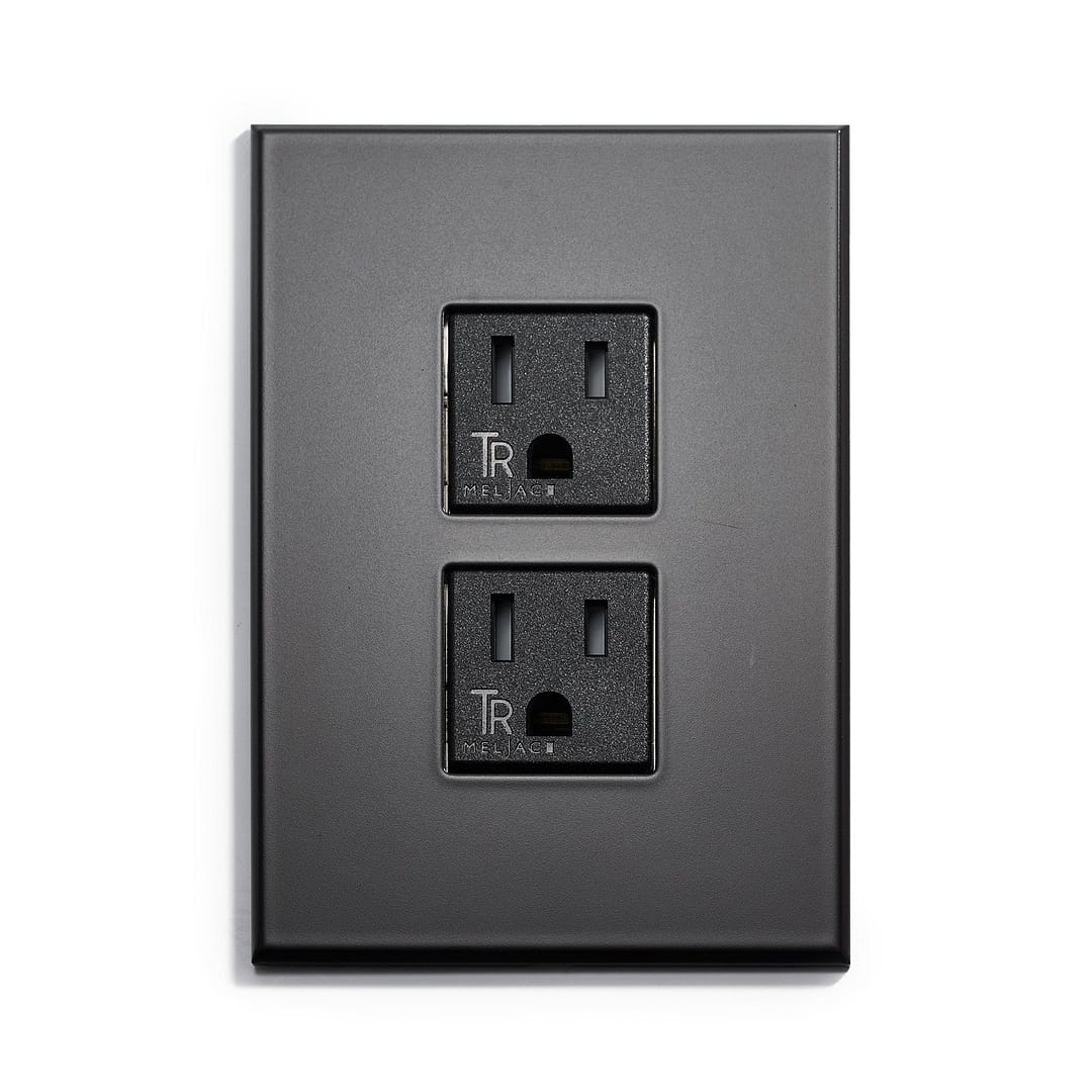 A black wall plate with two outlets on it.