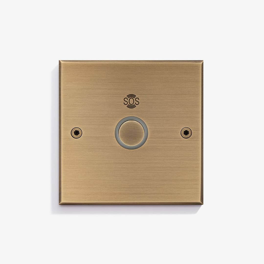 Elegant gold-toned emergency sos button mounted on a wall.