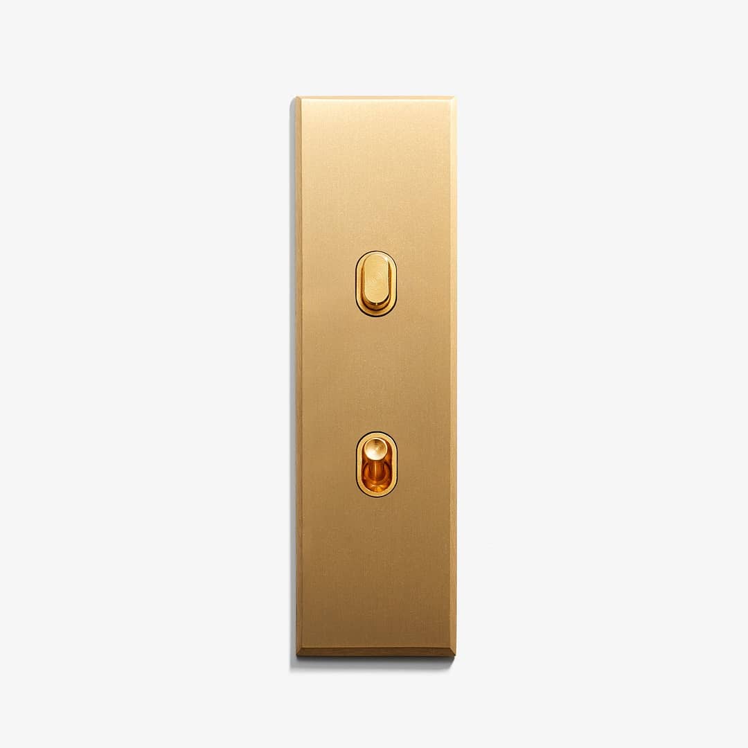 A golden elevator panel with two buttons, upper for ascending and lower for descending floors.