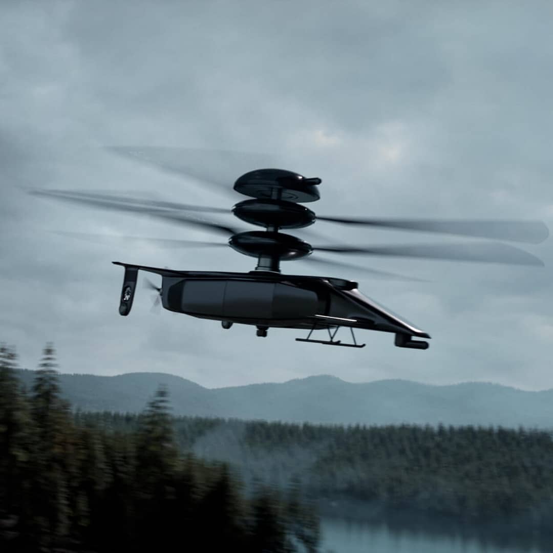 aviation-sbs A futuristic drone with dual rotor blades flies over a forest and lake, against a cloudy sky. The sleek, black design suggests advanced technology and innovation.