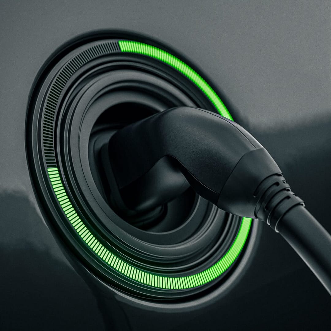 fast-charge-v2 Close-up of an electric vehicle charging port with a plugged-in charger. A circular LED indicator surrounding the port glows green, indicating the charging status on a sleek, dark surface.