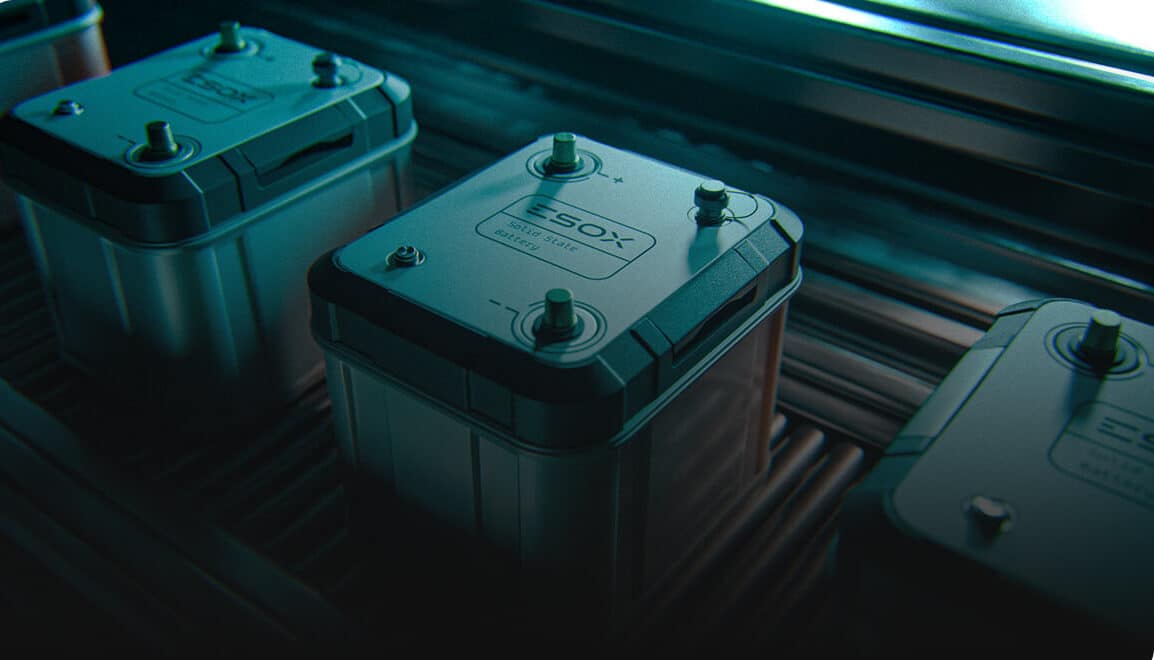 Three industrial batteries labeled “ESOX” are positioned on a conveyor belt under teal lighting, suggesting a manufacturing or assembly process in a factory setting.