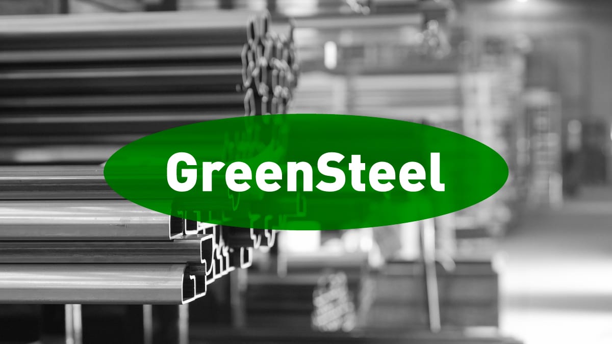 Stacks of steel beams in a warehouse, shown in black and white, with a green oval overlay in the center displaying the word "GreenSteel" in bold white letters.