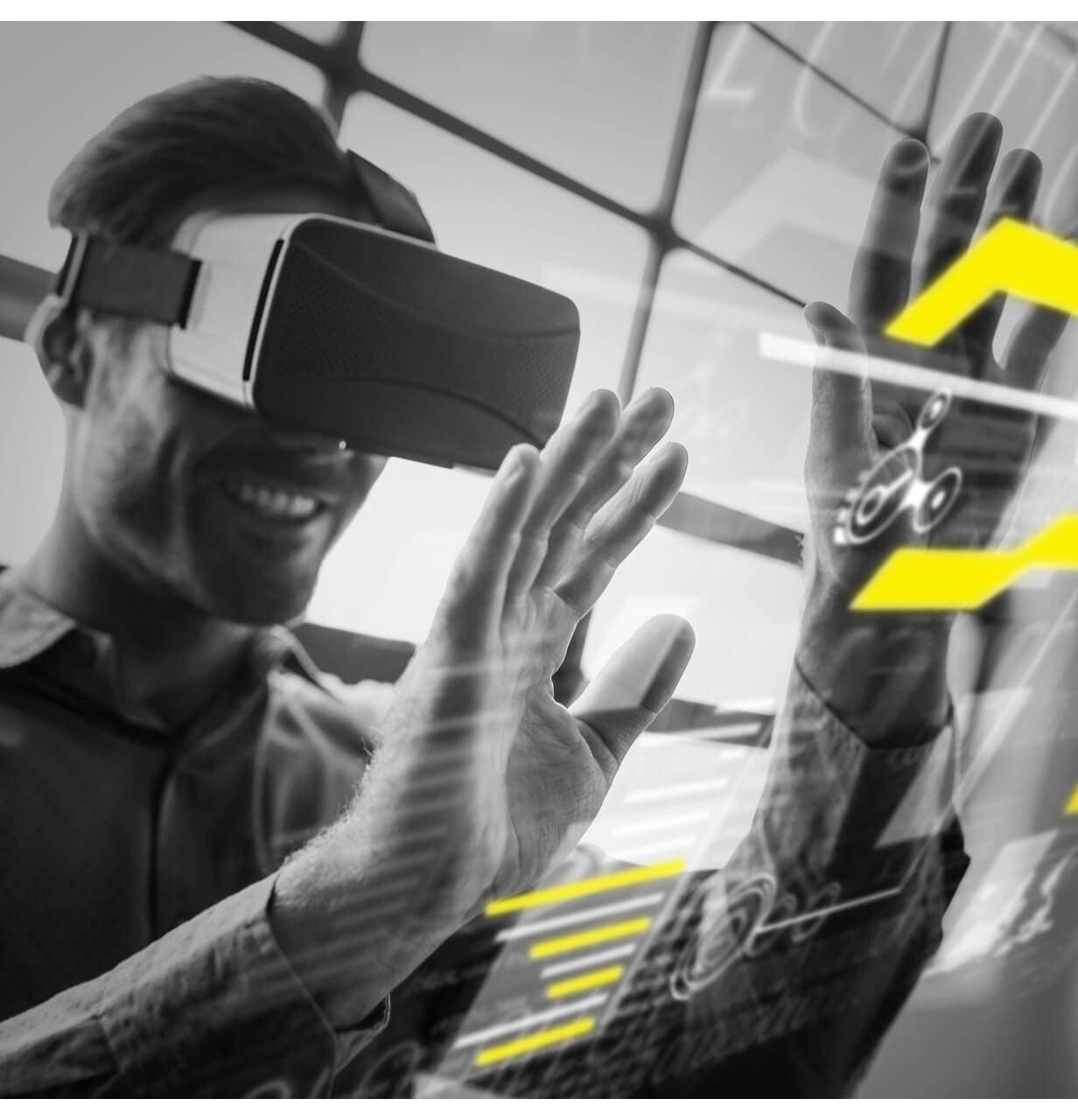 A man wearing virtual reality goggles smiles and interacts with floating digital graphics, featuring bright yellow highlighted elements, in a futuristic setting.