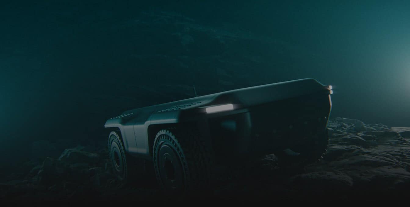A four-wheeled, rugged robotic vehicle with headlights navigates a dark, rocky terrain, illuminated by faint blue light, suggesting an exploration or search mission in a low-light environment.