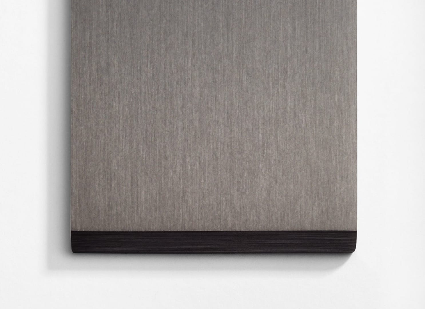 A gray and black piece of wood hanging on a wall.