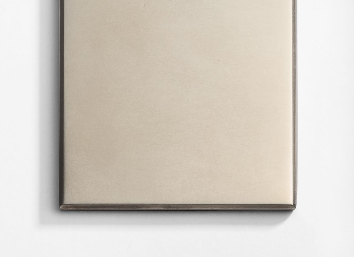 A close-up of a smooth, rectangular metallic surface with slightly rounded edges, placed on a white background.