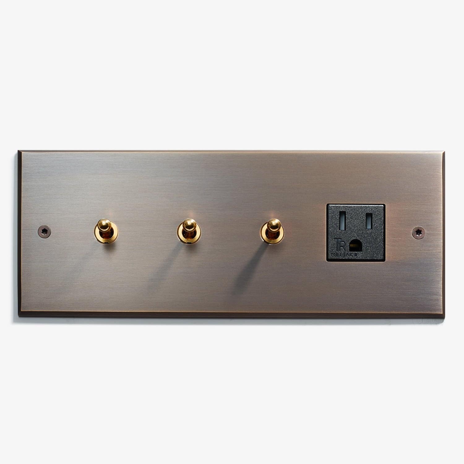 A bronze-colored wall plate featuring three circular toggle switches and one electrical outlet on a light background.