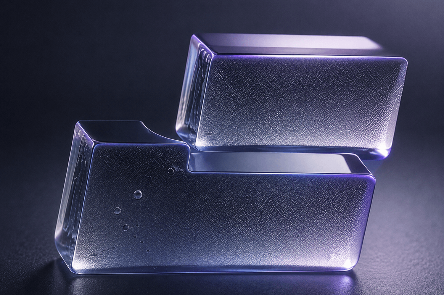 Two translucent, rectangular glass blocks with frosted surfaces are stacked askew against a dark purple background, with soft purple light outlining their edges.
