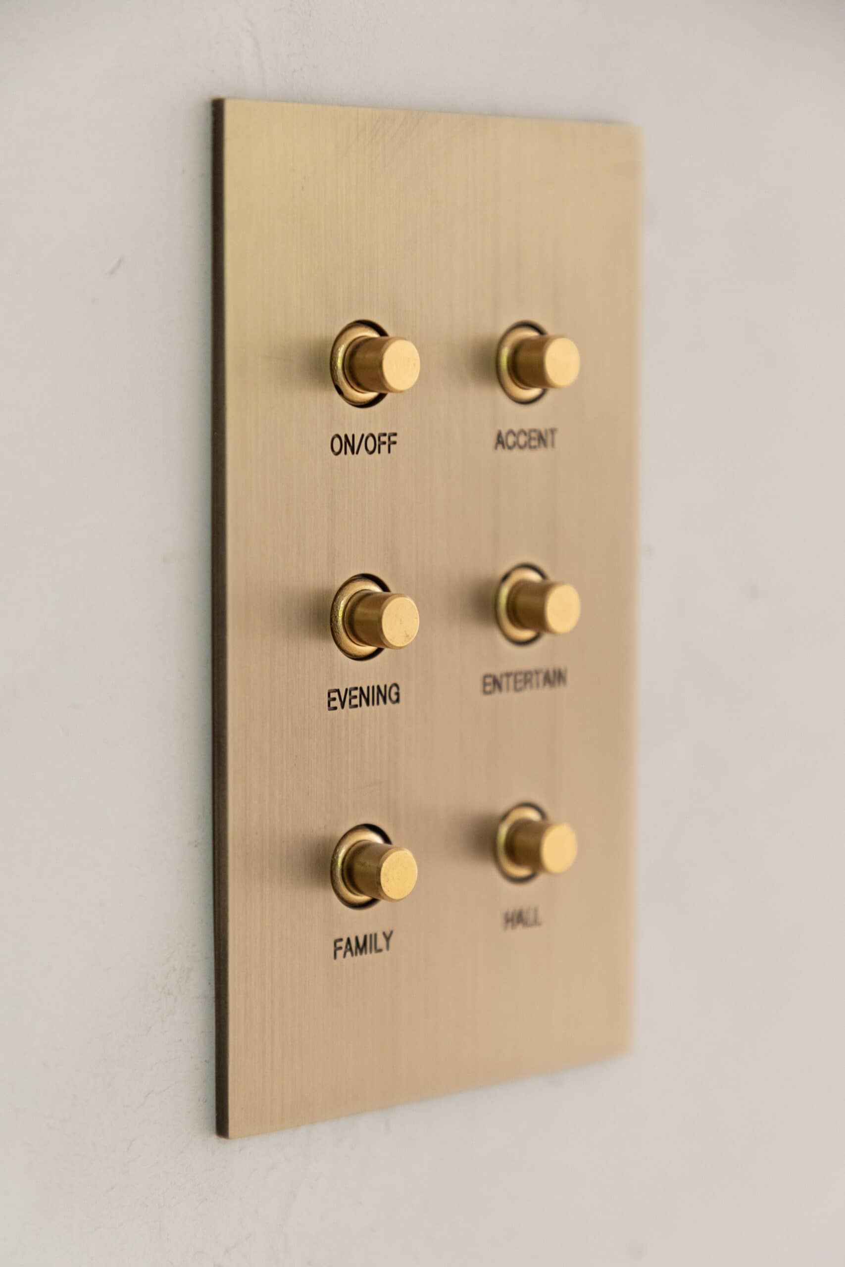 A brass wall switch panel with a number of buttons on it.