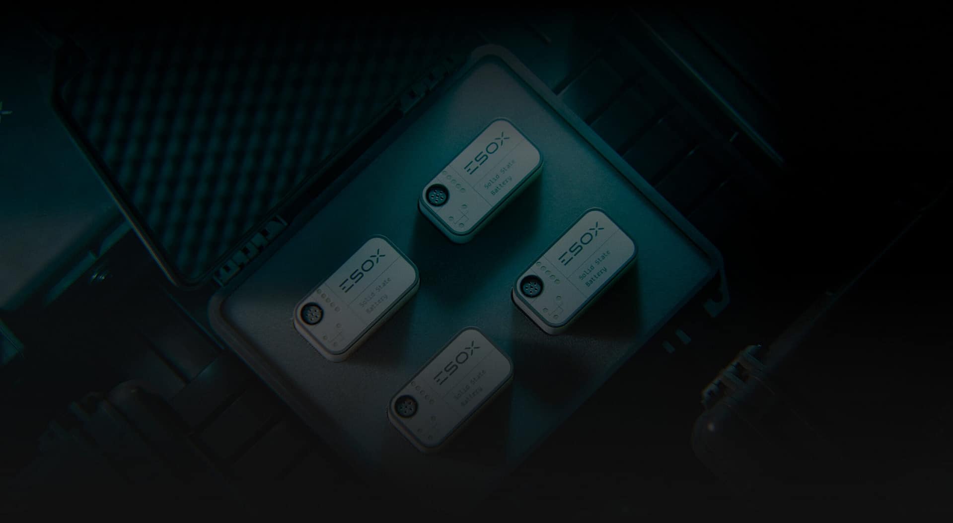 Four small rectangular electronic devices labeled "ISOX" are neatly arranged in a protective foam case, suggesting specialized equipment or sensors in a professional setting. The image is dimly lit.