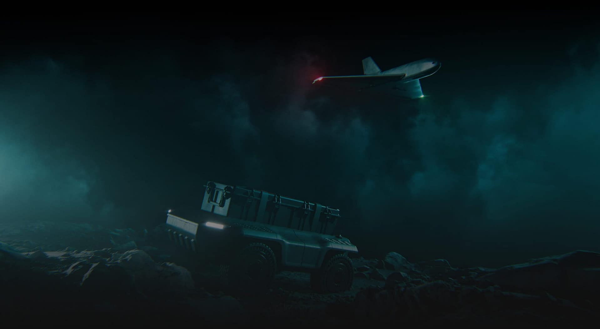 A rugged unmanned ground vehicle sits on rocky terrain at night, illuminated by dim blue-green light, while a drone with a red light flies above through a misty, clouded sky.