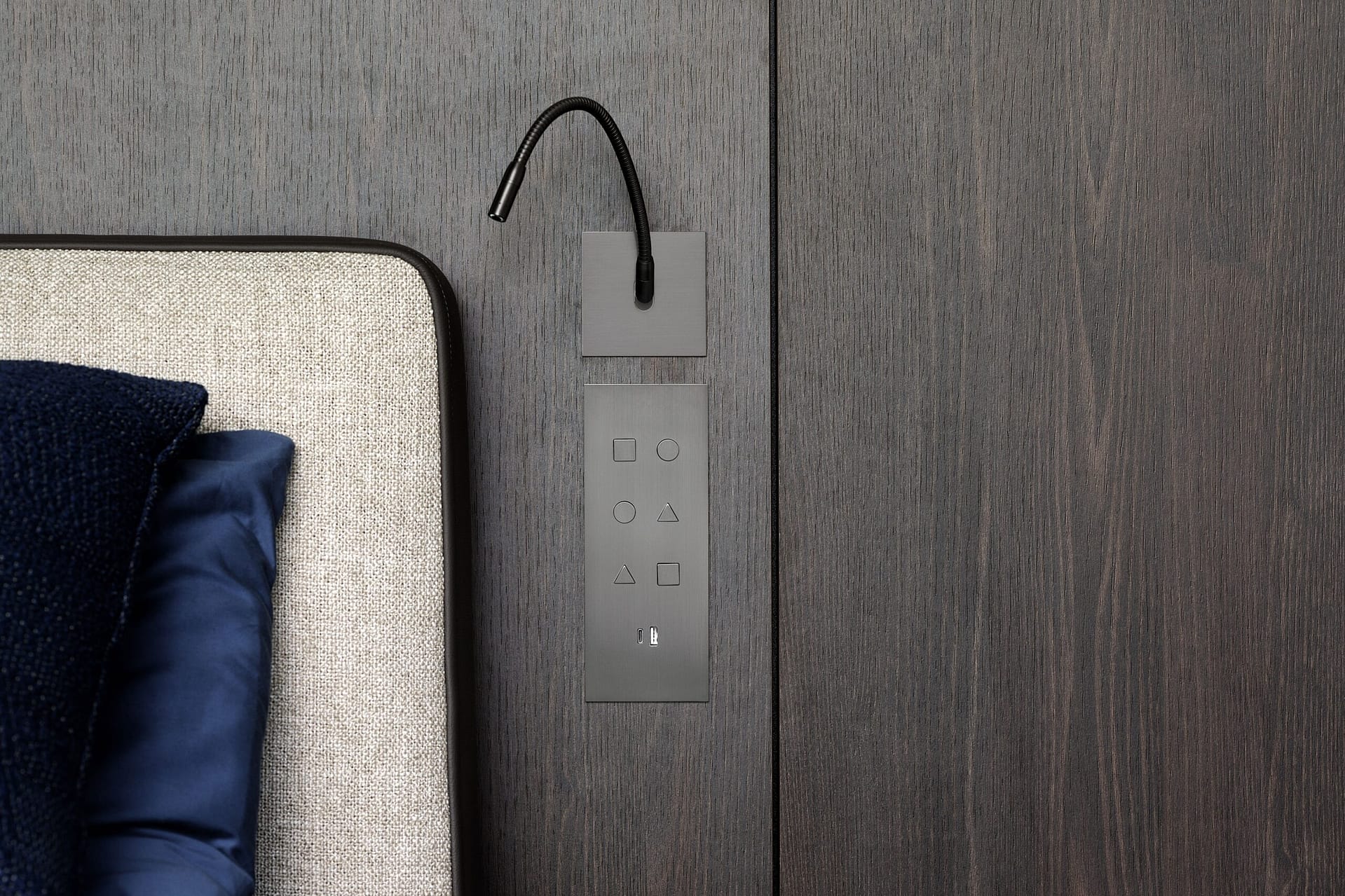 A bed with a blue pillow and a black headboard.