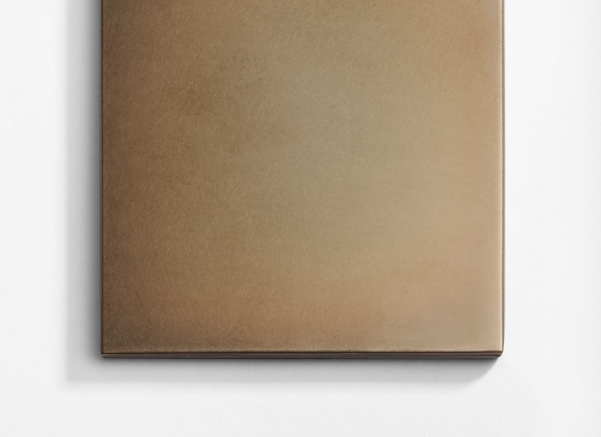 A close-up of a square, smooth, matte brown tile placed on a white surface, with its bottom and left edges visible.