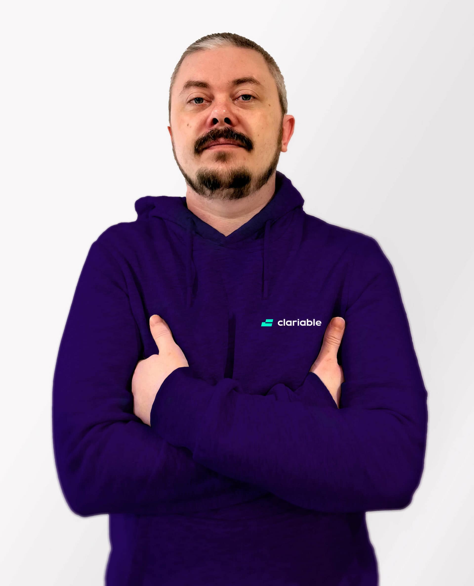 Dmitry A person with short hair and a goatee stands confidently with arms crossed, wearing a purple hoodie with a small logo on the chest. The background is a light gray gradient.