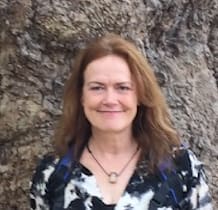 A woman standing in front of a tree.