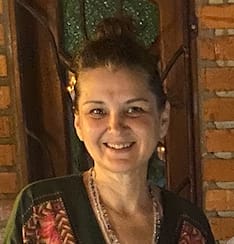 A woman smiling in front of a brick wall.