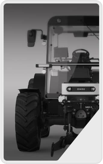 A front view of a modern tractor with large tires and visible cab windows, steering wheel, and headlights, shown in grayscale with a partial white border on the right corner.