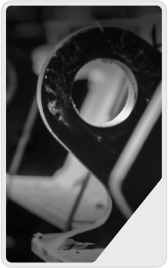 Close-up black and white photo of a metal object with a circular hole near the top, resembling a map pin icon, set against a blurred background.