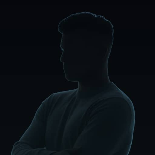 Silhouette of a person with short hair, arms crossed, and facing slightly to the left against a dark background. Facial features are not visible due to shadow and lighting.