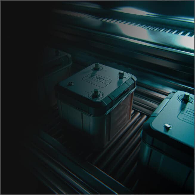 A close-up of a metallic battery unit with visible bolts and embossed labeling, set on a conveyor belt under blue-tinted industrial lighting.