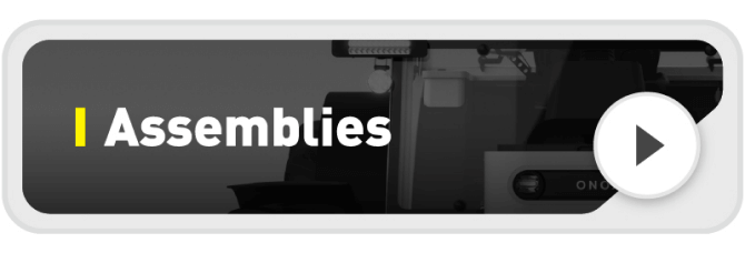 A rectangular banner with the word "Assemblies" in bold white text beside a yellow vertical line, partially overlaying a grayscale image of machinery, and a white play button on the right.