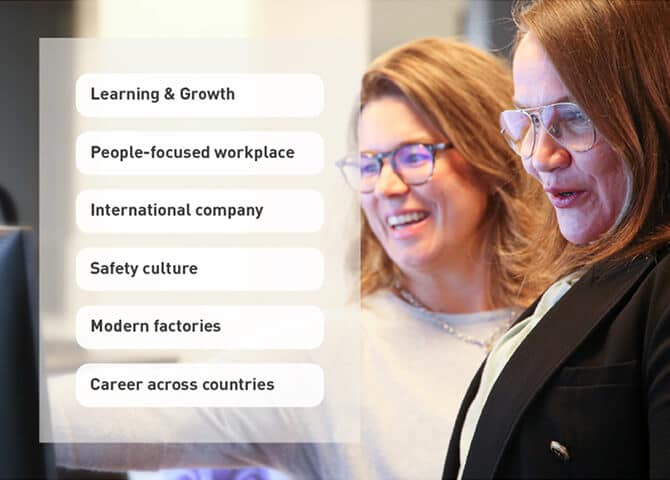 Two women, both wearing glasses and business attire, smile while looking at a screen. To the left, text boxes list workplace benefits like learning & growth, safety culture, and international opportunities.