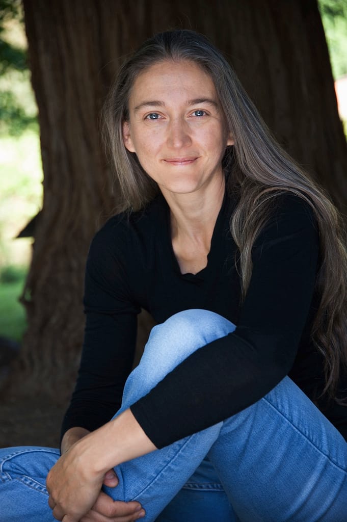 A woman sitting in front of a tree.