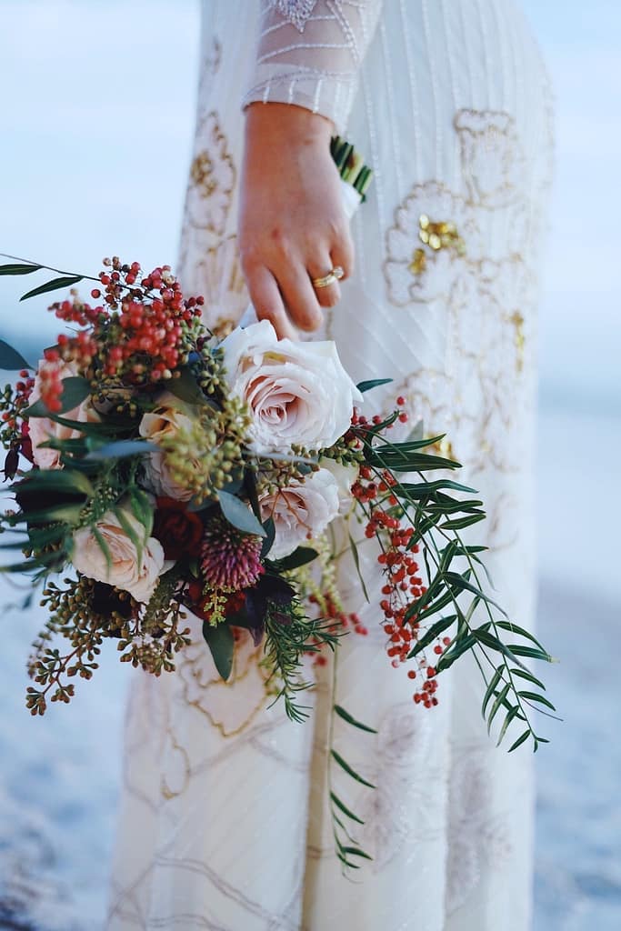 Colorful wedding flowers hanging from the hand of the bride