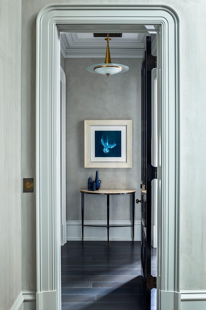 A hallway with a blue door and a framed painting.