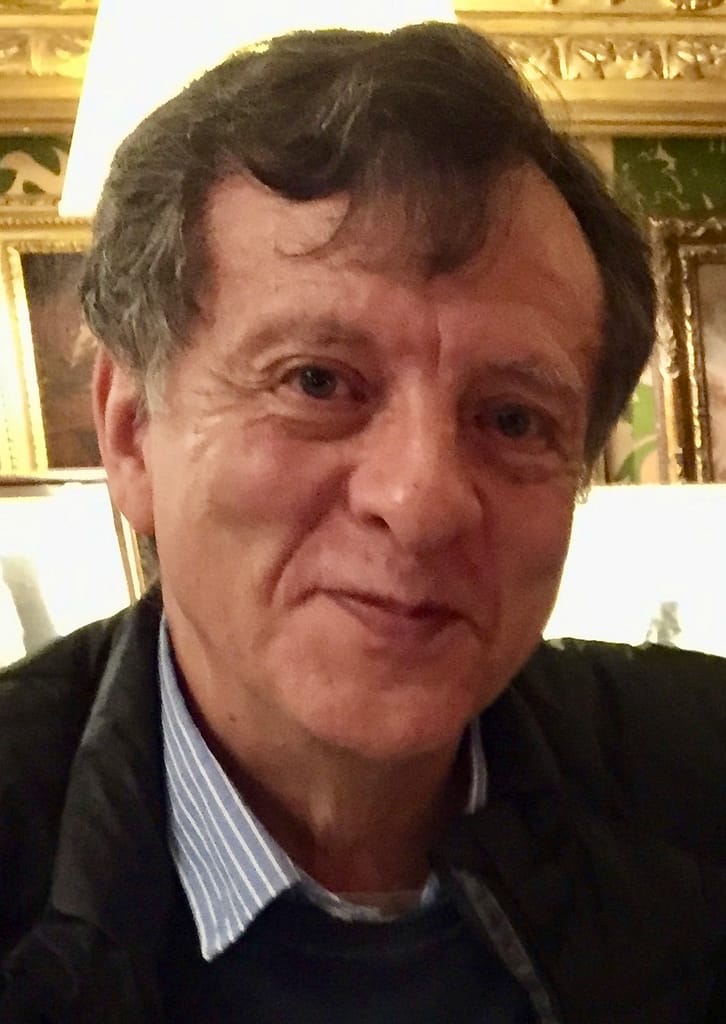 A man in a black jacket is smiling for the camera.