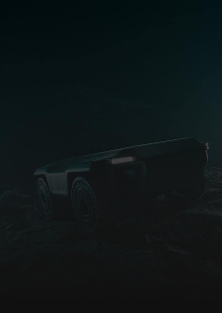 A dark, moody image of a four-wheeled robotic vehicle with headlights on, positioned on rough, rocky terrain in a low-light environment.