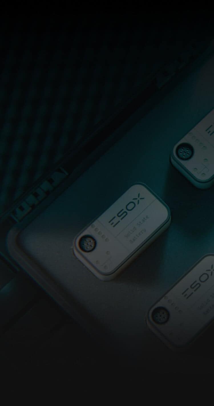 Close-up of several rectangular electronic devices labeled "ESOX" with visible screws, resting in a foam-lined case. The image has a dark, teal-toned lighting.