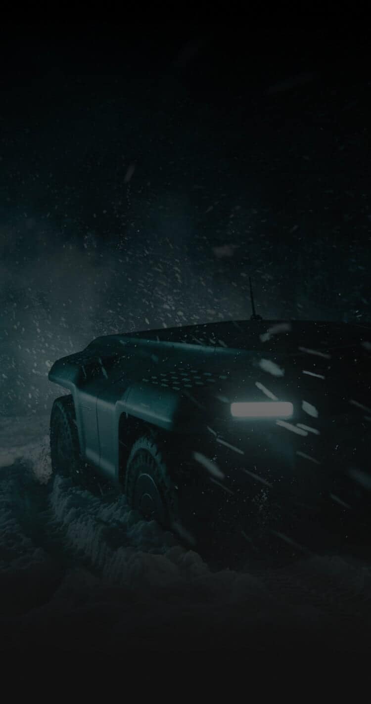 A futuristic armored vehicle with bright headlights drives through heavy snow at night, surrounded by falling snowflakes and dark, misty surroundings.